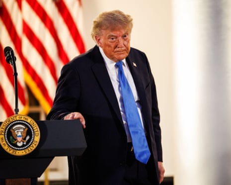 a man in a suit stands with his hand on a lectern