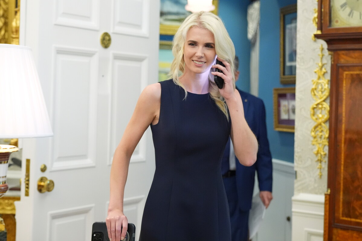 White House aide Natalie Harp is pictured using a cell phone as President Donald Trump speaks during an event about drug prices, in the Oval Office of the White House, Monday, Aug. 31, 2026, in Washington. (AP Photo/Jacquelyn Martin)