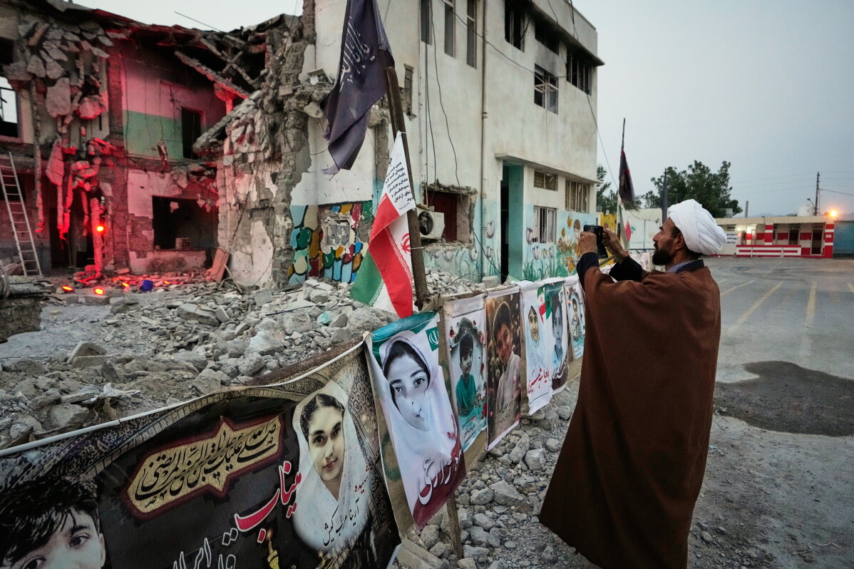 A cleric takes a photograph at the shattered Shajareh Tayyebeh school, which has become a place of mourning and a memorial to those killed in a U.S. airstrike on Feb. 28, in Minab, southern Iran, Monday, Sept. 7, 2026. (AP Photo/Vahid Salemi)