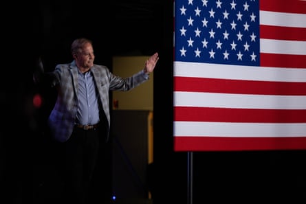 A man waves next to a US flag
