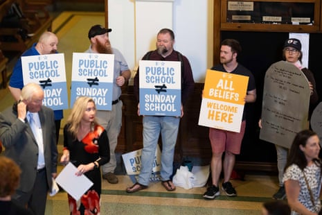 People hold signs that say 'Public School Does Not Equal Sunday School' and 'All Beliefs Welcome Here'