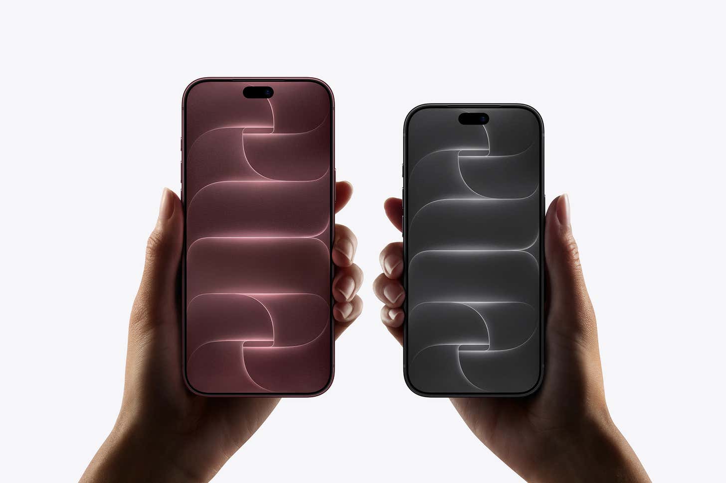 Two hands hold an iPhone 18 Pro Max on the left and an iPhone 18 Pro on the right side-by-side against a plain white background.