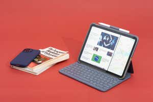 An iPad in a Logitech Slim Folio case sitting next to a stack of books and a smartphone.