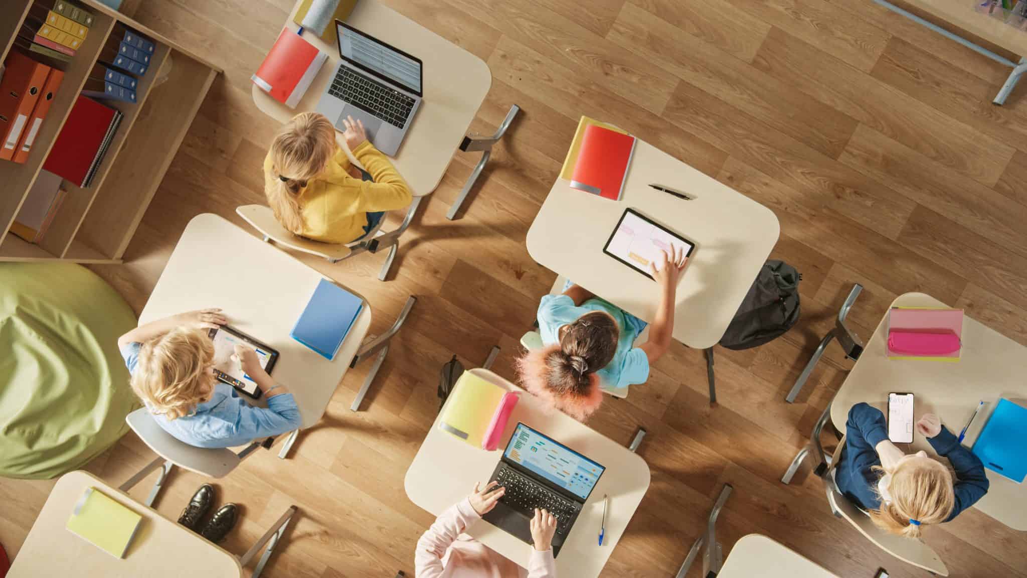 Tomada do alto de crianças sentadas em carteiras escolares