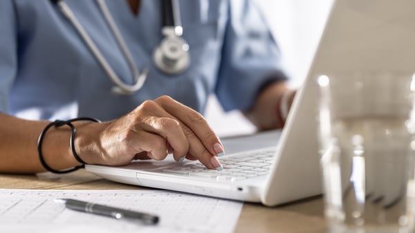 A doctor works on a laptop